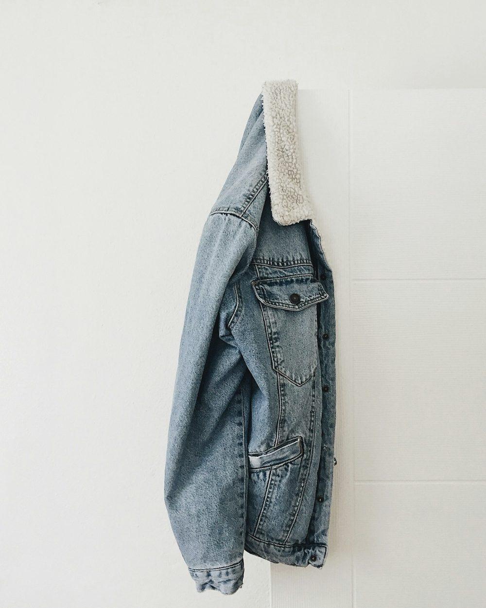 Washed denim jacket hanging on a white wall